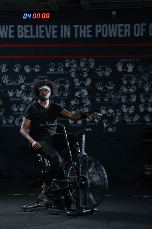 Free A man working out on a stationary bike in a dimly lit gym setting. Stock Photo