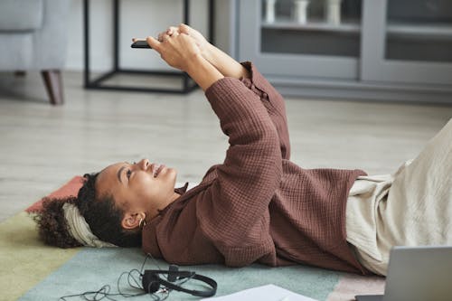 Free Woman Lying on Floor Using Cellphone Stock Photo