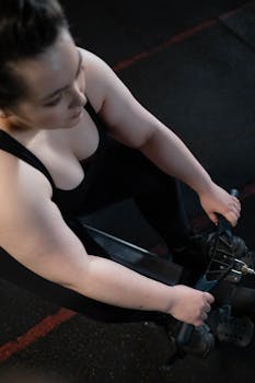 Top view of a woman working out on a rowing machine in the gym, focusing on fitness and wellness.