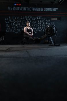 Woman using rowing machine in gym, embracing fitness and body positivity.