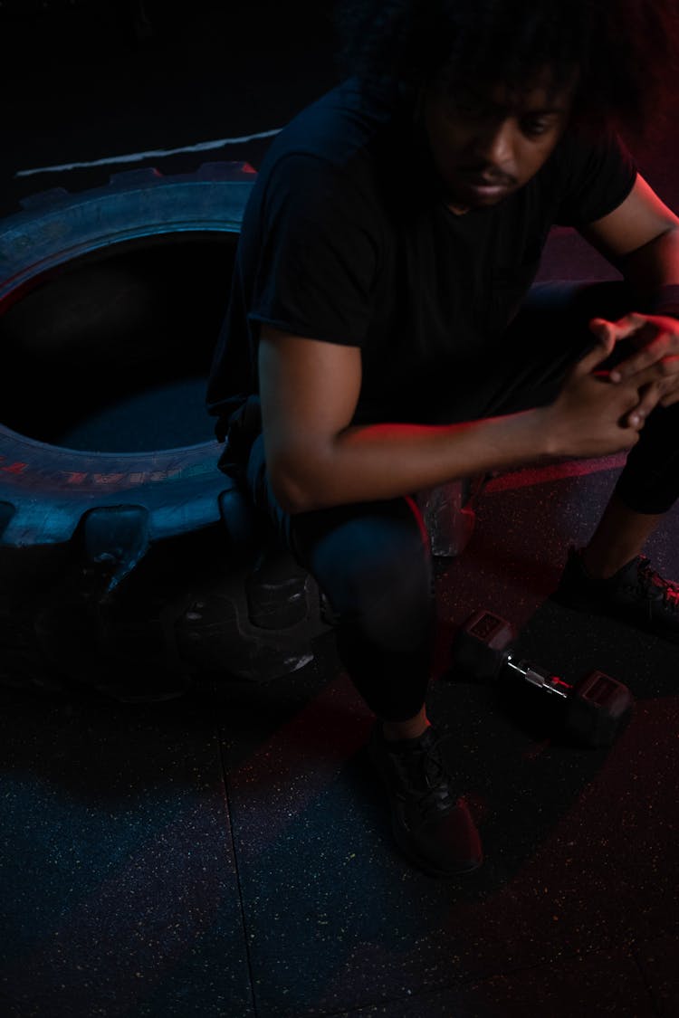 Man In Black Crew Neck T-shirt Sitting On Huge Tire