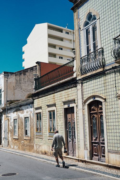Free A man walking down a vintage street in Faro, Portugal, showcasing architectural charm. Stock Photo