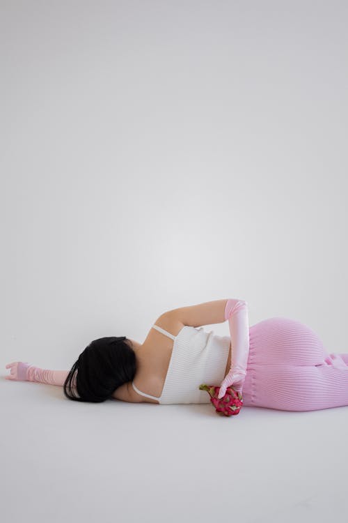 Person Lying on the Floor while Holding a Dragon Fruit