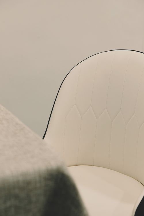 Free Minimalist white chair with black trim beside a textured grey fabric, offering a modern interior design vibe. Stock Photo