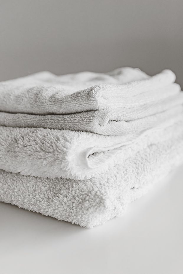 Neatly folded white cotton towels stacked on a surface, by ROMAN ODINTSOV on Pexels