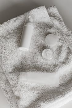 Elegant display of white cosmetic bottles on a soft towel, perfect for spa or skincare themes.