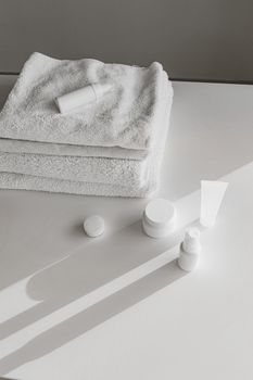 Simple, minimalist setup of skincare products and towels on a white surface, perfect for beauty ads.