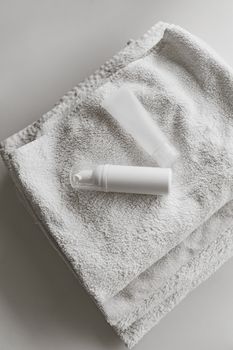 Close-up of skincare bottles on a soft white towel, offering a minimalist aesthetic.