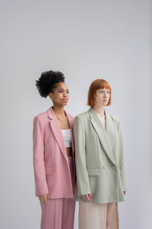 Free Serious multiethnic female models wearing elegant outfits standing close against gray background and looking away with attention Stock Photo