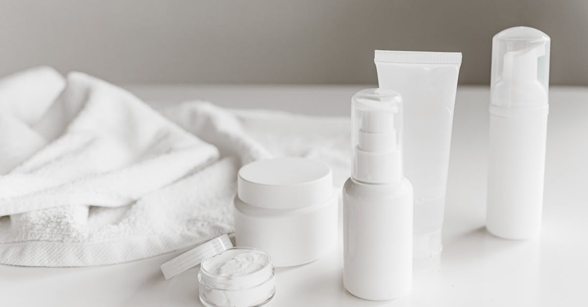 Clean and stylish display of skincare products on a white surface with a towel backdrop. Clean and stylish display of skincare products on a white surface with a towel backdrop.