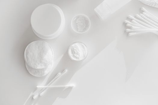 Flat lay of skincare essentials with cotton pads and cotton swabs on a white background.