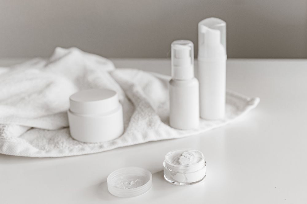 White conditioner pump bottle and cream jars on a towel