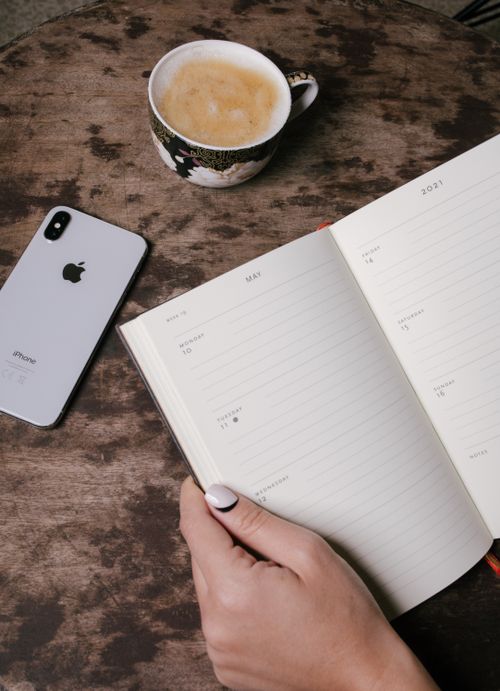 Free Top view of coffee cup, smartphone, and open planner on a rustic table. Stock Photo