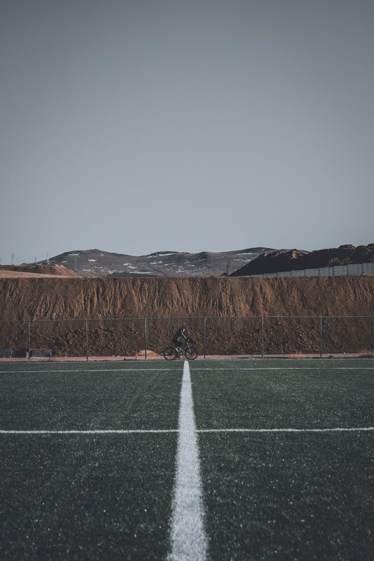 Person Cycling On Football Pitch