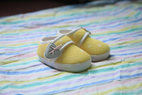 Yellow Pair of Baby Shoes on Colorful Textile