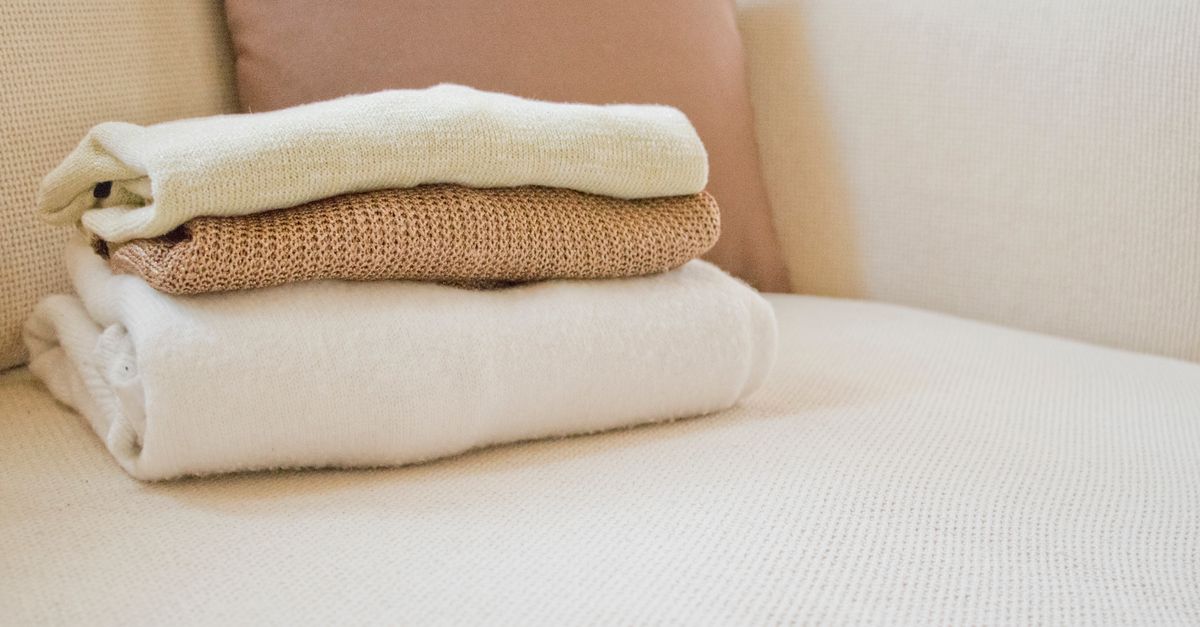 Opgevouwen gebreide truien naast een wasmand