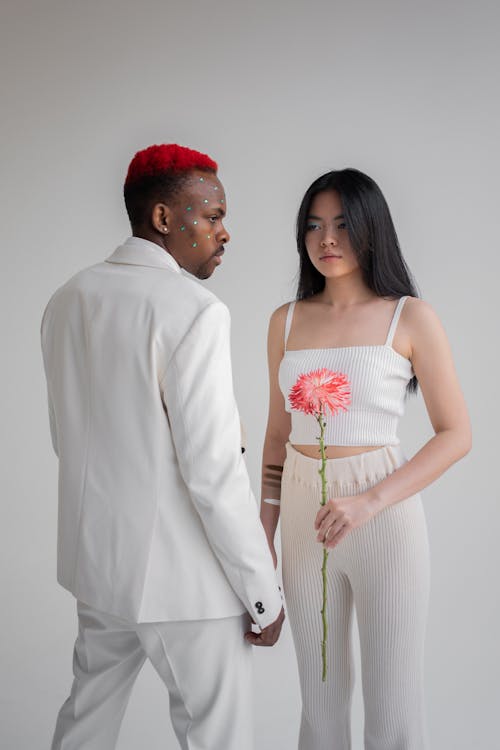 Asian woman with flower looking at black man