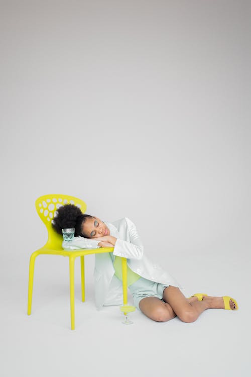 Black woman putting head on bright neon yellow chair