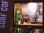 在时尚酒吧内，男子使用智能手机，周围充满活力的植物和舒适的氛围