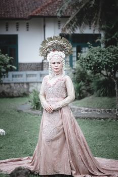 Woman in traditional attire with ornate headdress posing gracefully outdoors.