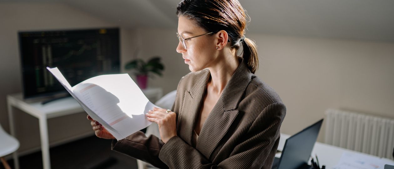 Vrouw met bril vergelijkt financiële documenten aan een bureau
