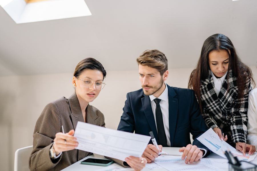 Three colleagues reviewing charts and reports together at a desk