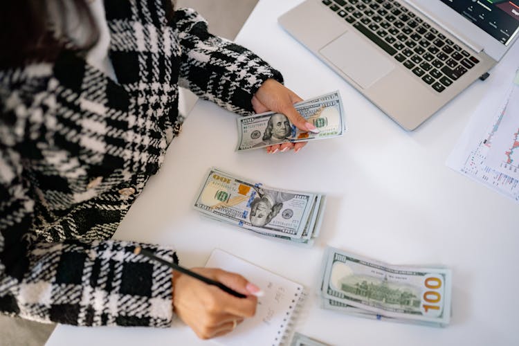 Hand Of A Woman Holding Cash And A Pencil