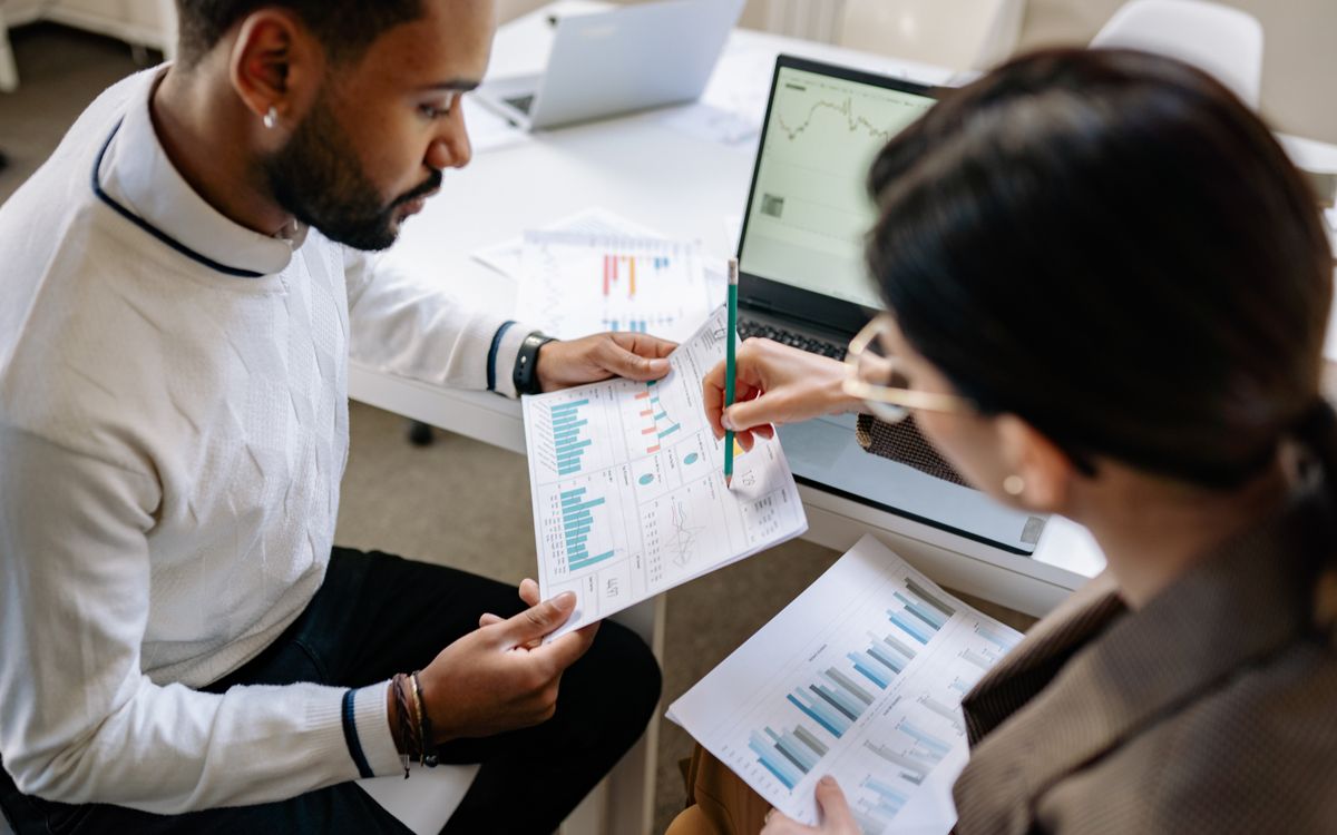 Two professionals reviewing data and graphs in a modern office setting for analysis.