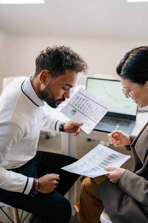 Man in White Long Sleeves Holding White Paper Discussing With Woman