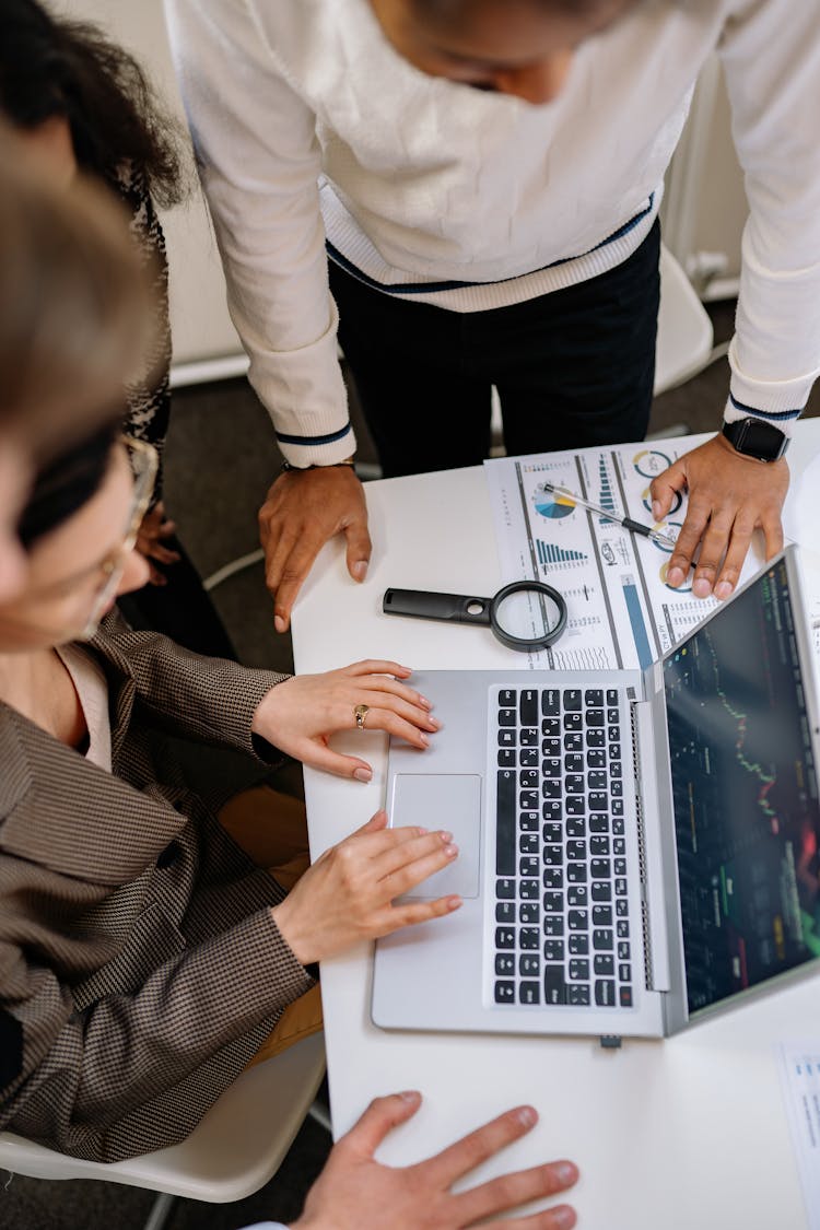 Top View Of Coworkers Gathered Around A Laptop