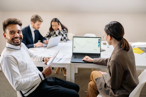 Free A group of professionals engaged in a collaborative meeting with charts and technology in a modern office setting. Stock Photo