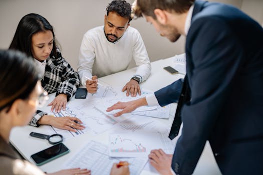 A diverse team collaborating in an office meeting, discussing papers with charts.