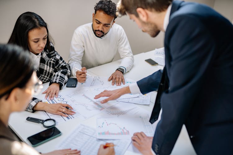 A Group Of People Working Together While Looking At The Papers On The Table