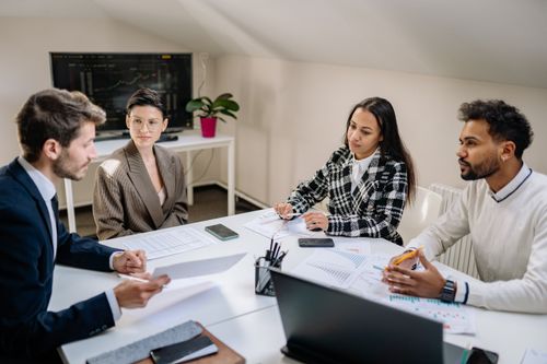 Free A diverse group of professionals collaborating in an office setting, engaged in a meeting around a table. Stock Photo