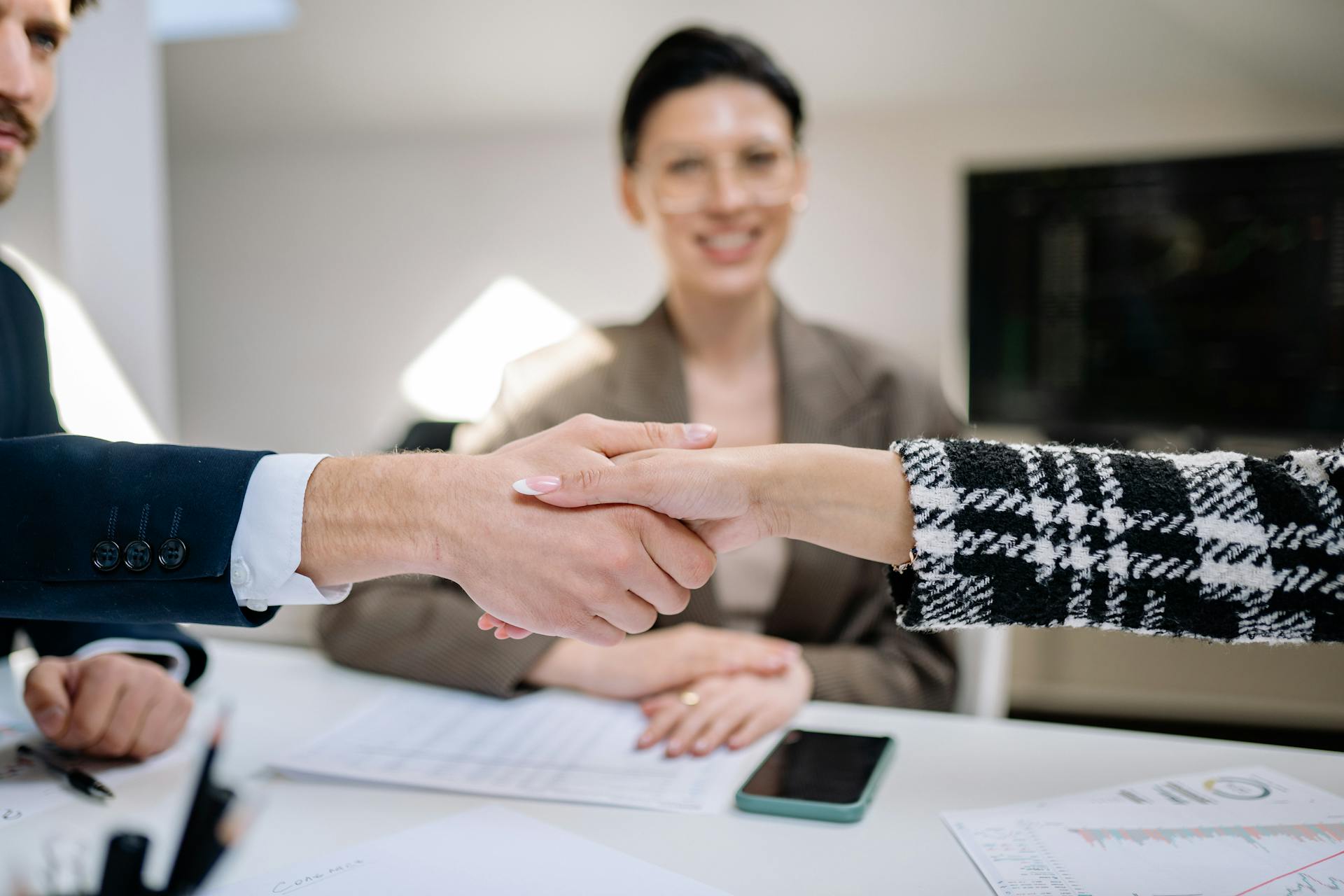 Professional handshake sealing a business deal with colleagues observing.