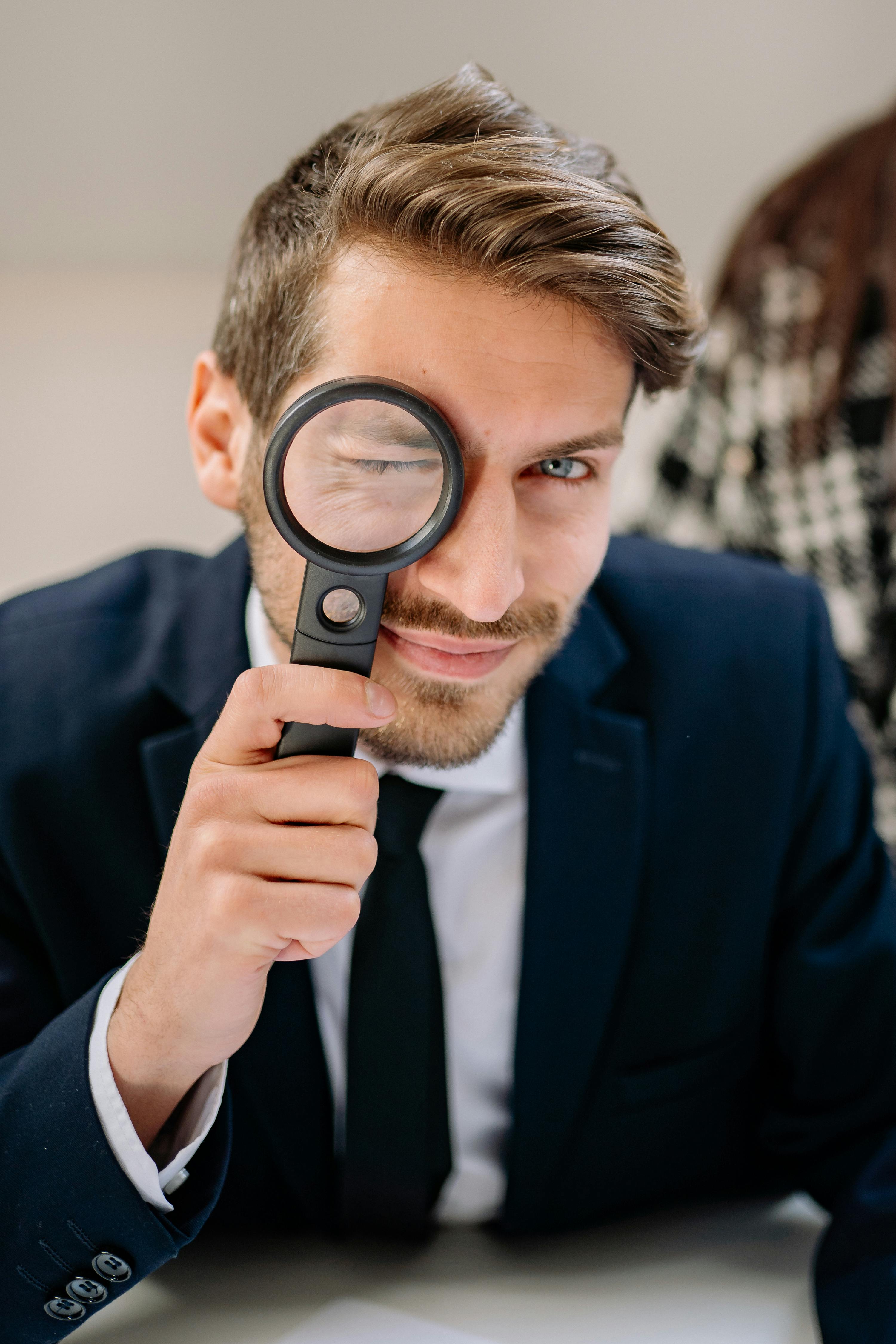 a man wearing a suit while holding a magnifying glass