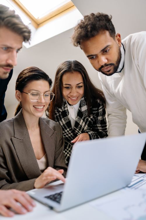 Free A diverse team of professionals happily collaborating on a laptop at the office. Stock Photo