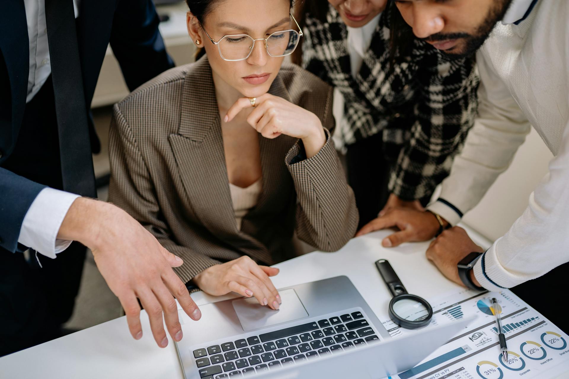 Team of professionals engaging in a collaborative project around a laptop in a modern office.