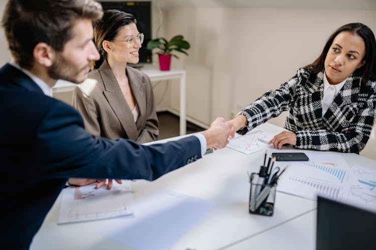 Man And Woman Sitting At Table While Shaking Hands