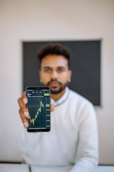 Man holding smartphone with stock market chart, focusing on financial growth.