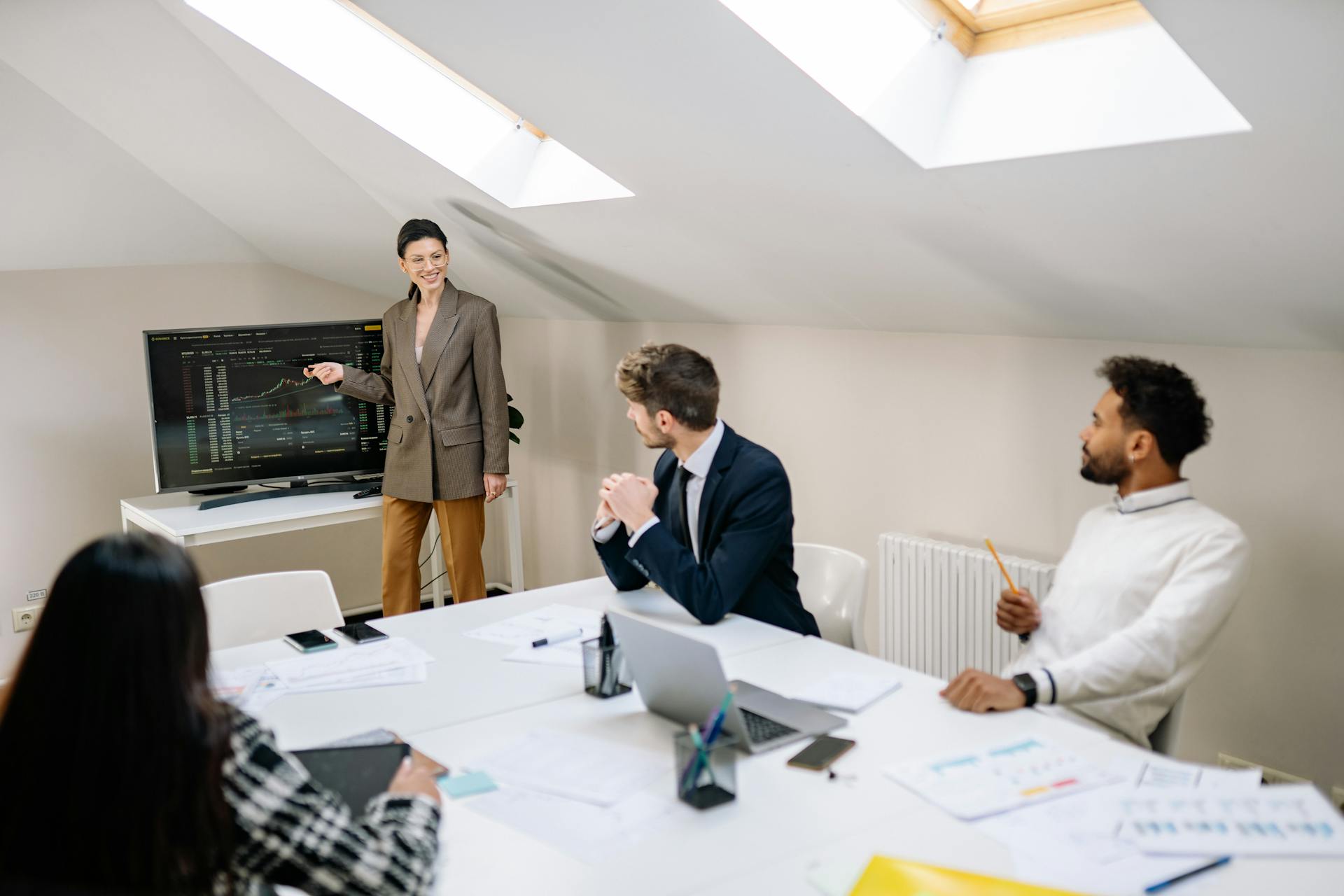 Team of professionals discussing stock market data in a well-lit office setting.