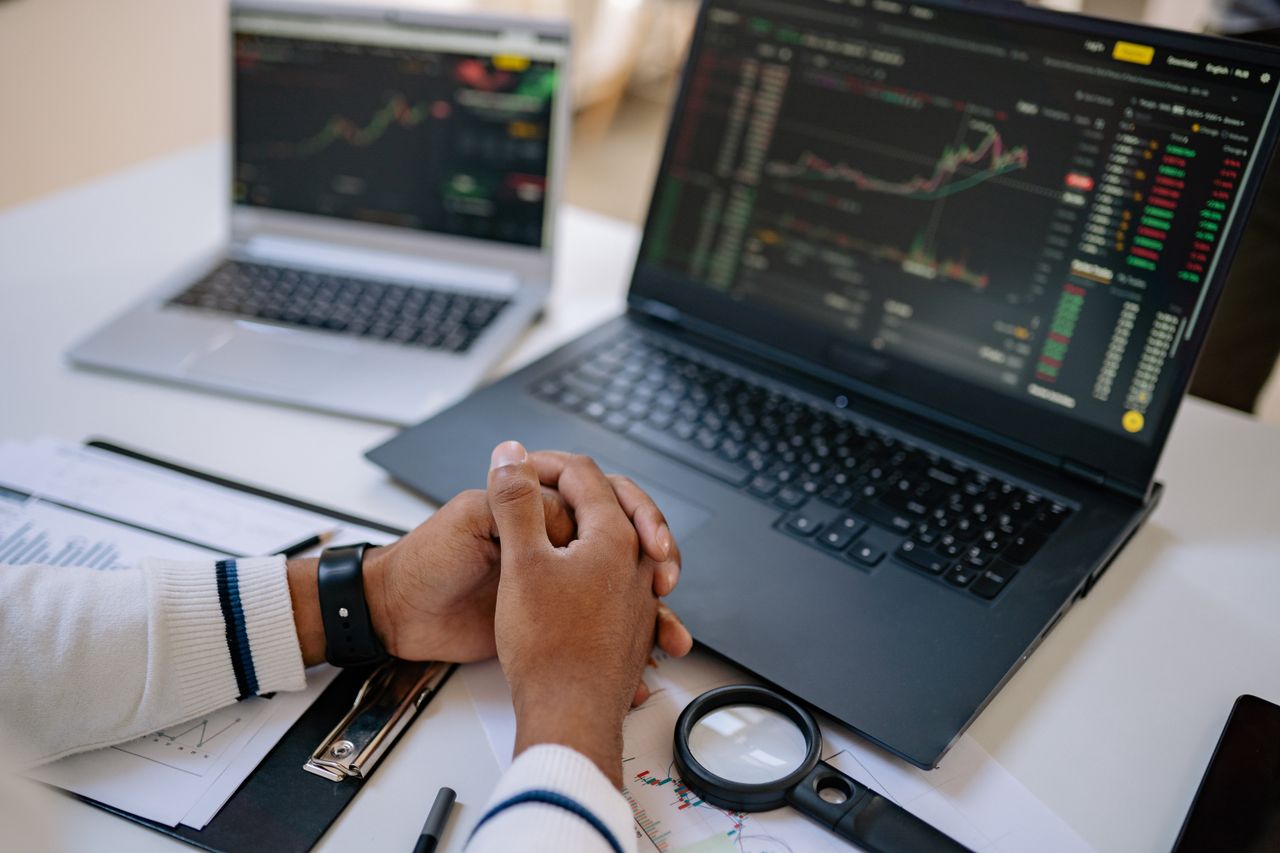 Man seated at a desk using laptops to monitor stock market trends and investments