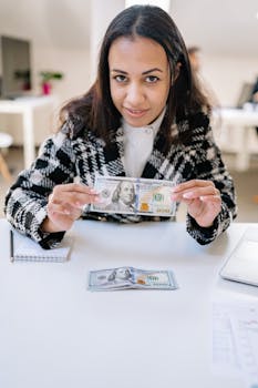 Portrait of a woman displaying cash with focus on American hundred dollar bill