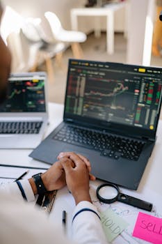 Person analyzing stock market trends on a laptop in an office setting.