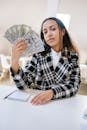 Woman in Black and White Checkered Dress Shirt Holding Fan of Banknotes