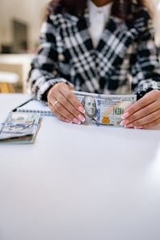Close-up of a woman's hands holding US dollars on an office desk.