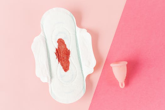A sanitary pad and menstrual cup on a pink background, highlighting menstrual hygiene.