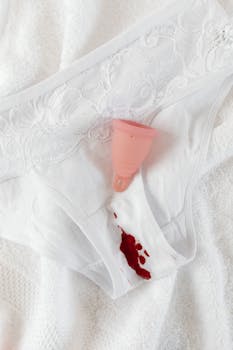 Lace underwear with a menstrual cup and blood stain for period awareness.