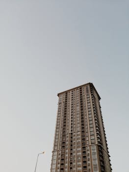 Low-angle view of a tall modern high-rise building against a clear sky, showcasing urban architecture.