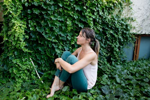 A Woman Sitting on Green Ivy Leaves